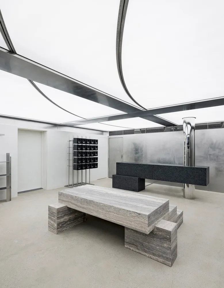 Minimalist concrete furniture and metal structures within an industrial interior design space.