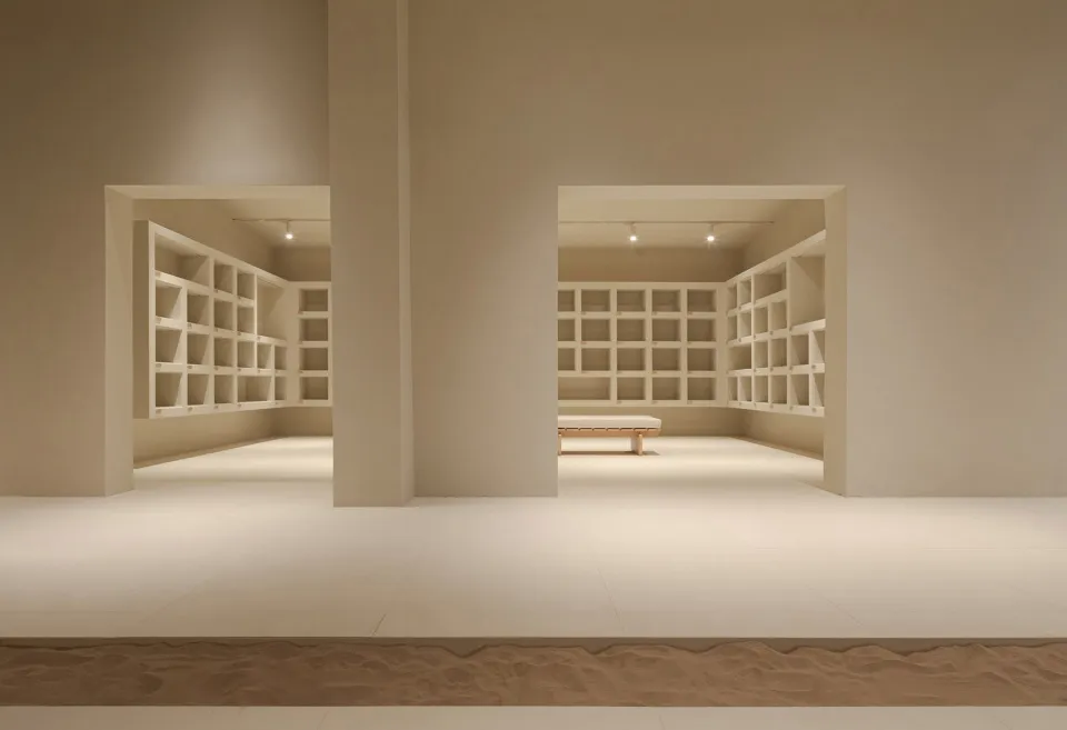 An empty minimalist interior space with concrete walls and wooden shelves.