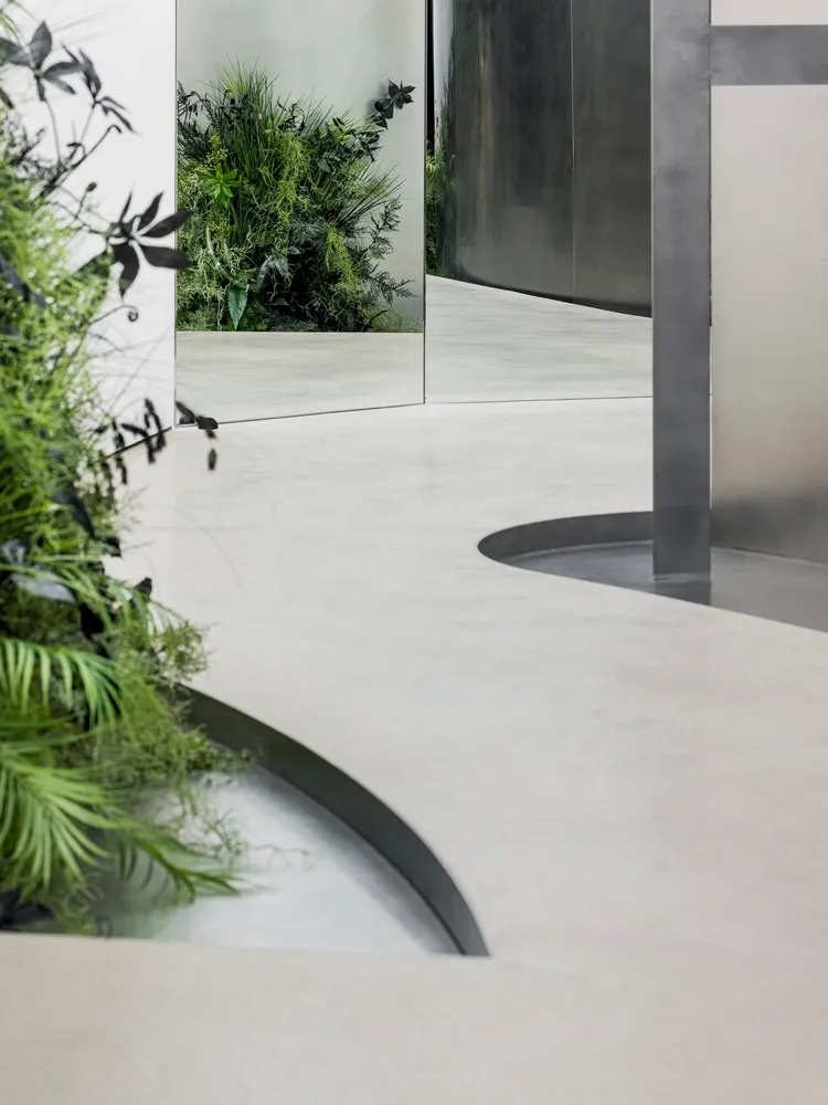 Modern industrial office space featuring a concrete floor, mirrored wall, and metal structural elements.