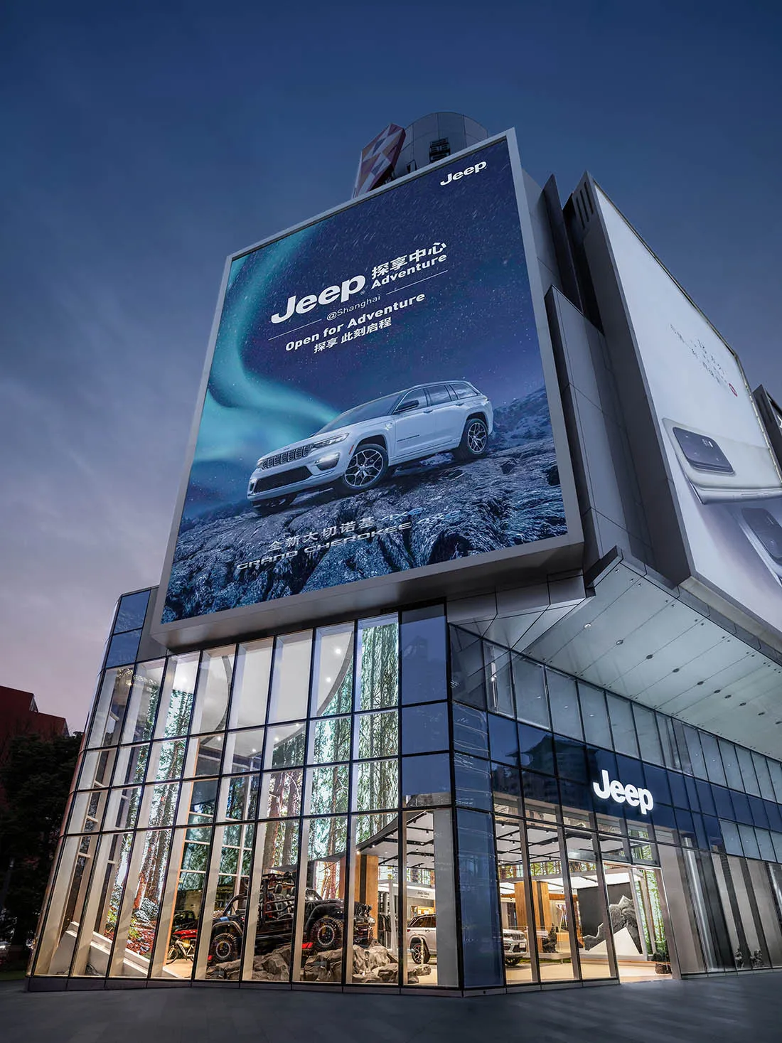 夜晚時分,一棟大型玻璃立面建築物,前面有大型 Jeep 廣告。