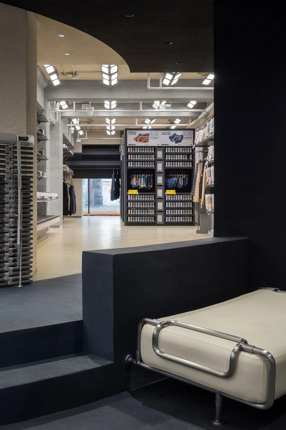 A modern retail space with concrete shelves, showcasing clothing and accessories.