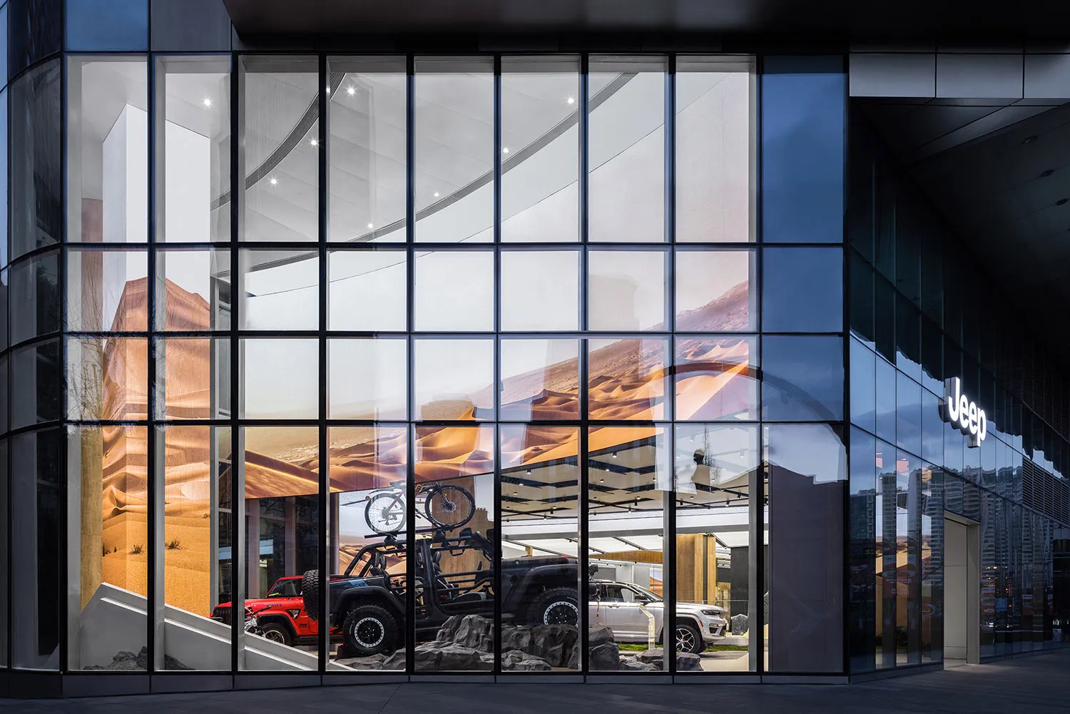 A modern storefront with large glass windows displaying a Jeep showroom.