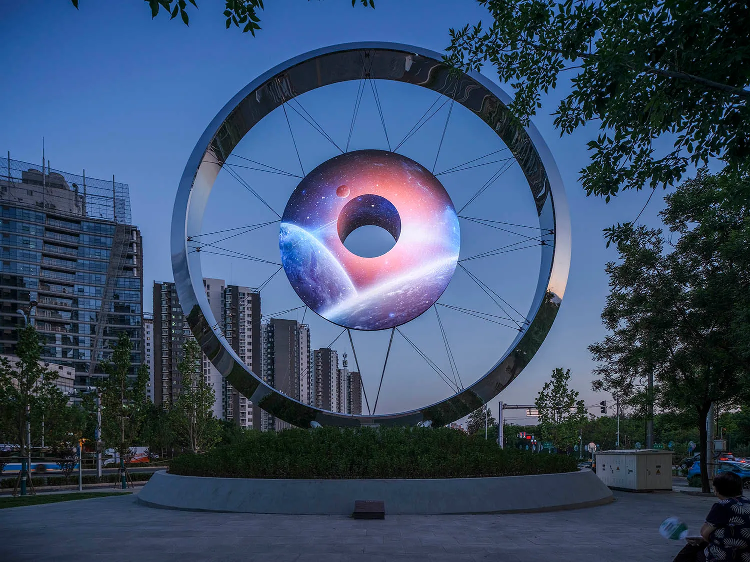 A large metallic sculpture depicting a black hole with a galaxy in the background.
