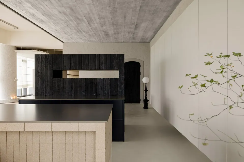 A modern interior space featuring concrete walls, wooden cabinets, and a stone countertop.