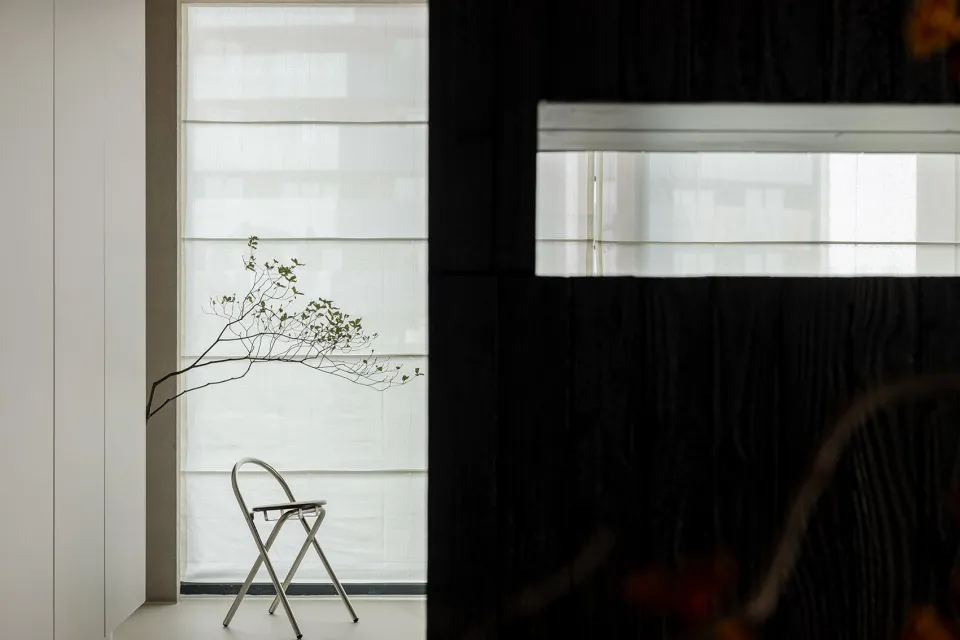 A minimalist bedroom with a modern metal chair and minimalist decor.