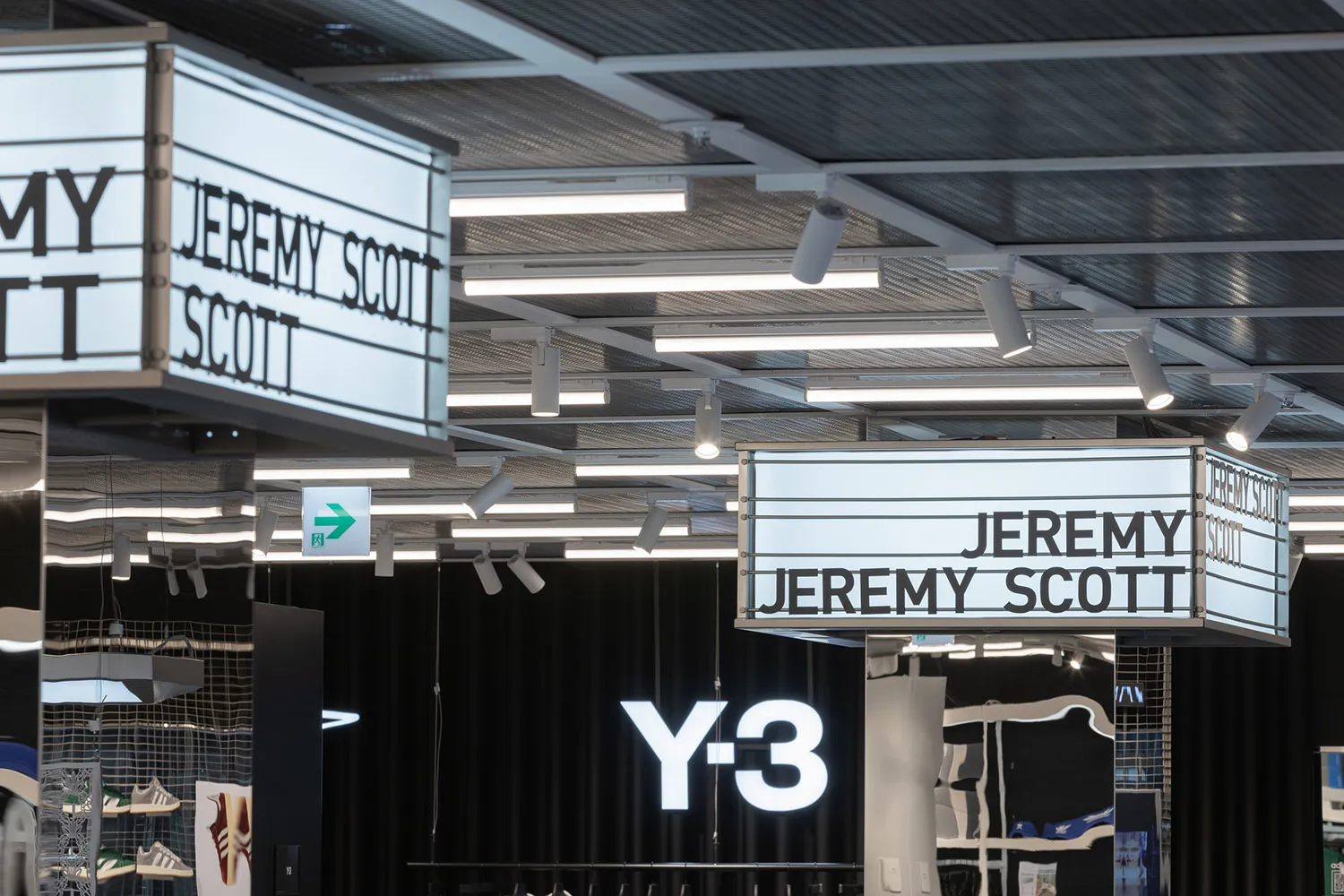 A retail space with illuminated signage featuring the name Jeremy Scott and Y-3, showcasing modern lighting design.