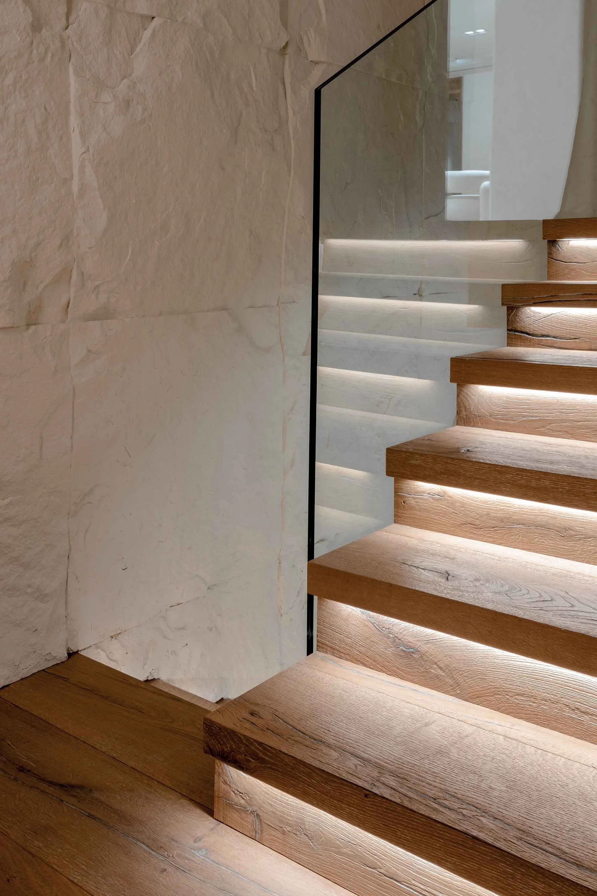 Modern staircase with concrete steps illuminated by embedded lights and wooden steps.