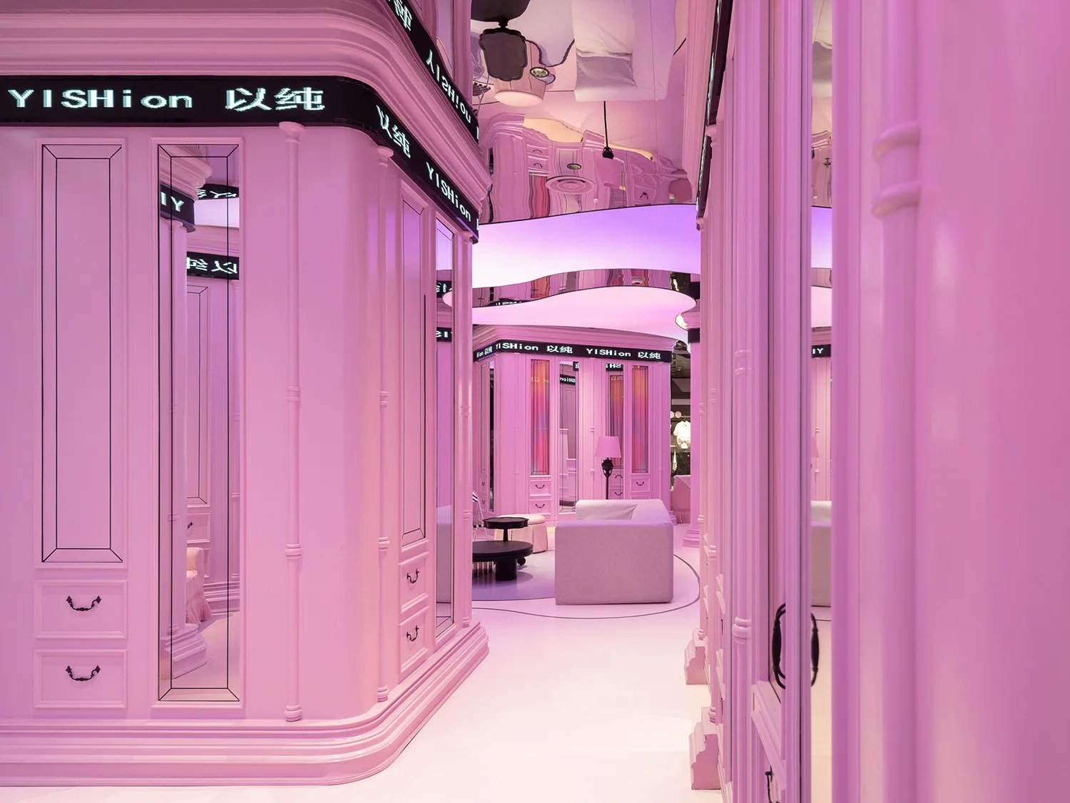 A retail shop featuring pink walls and mirrors, designed for shopping or fashion displays.