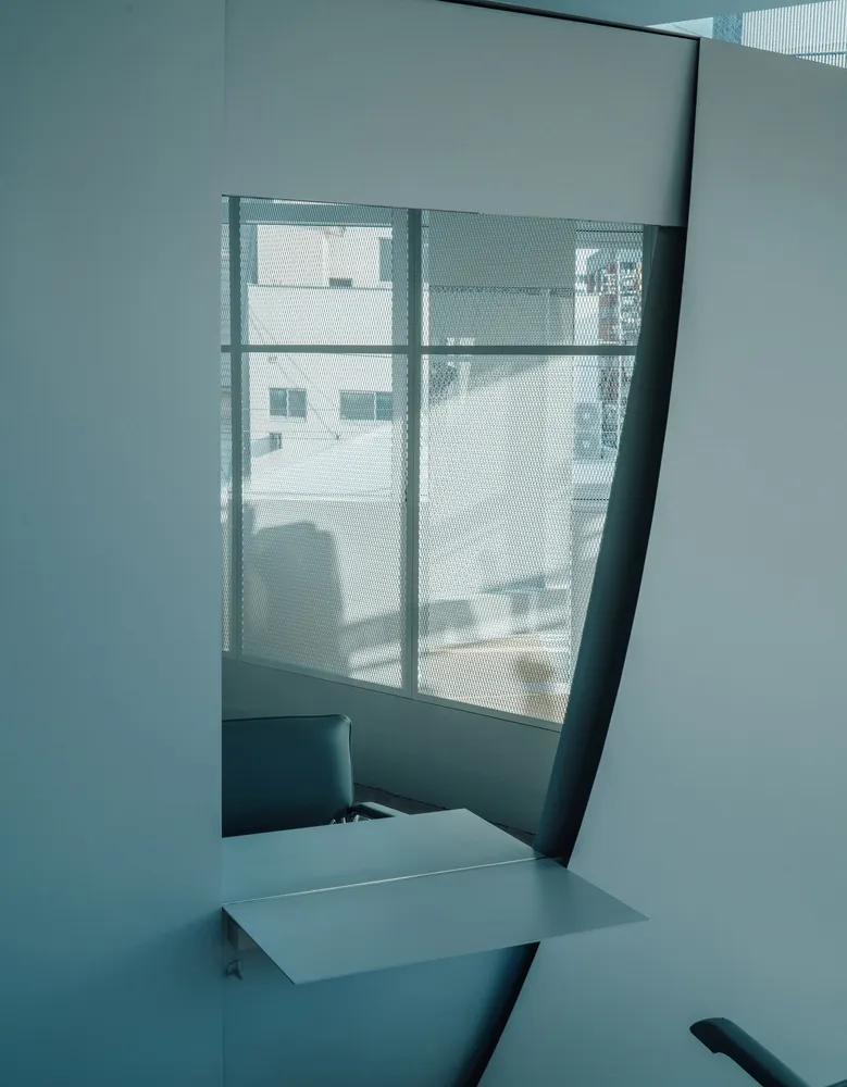 A minimalist chatroom interior with a modern window design, white walls, and metallic accents.