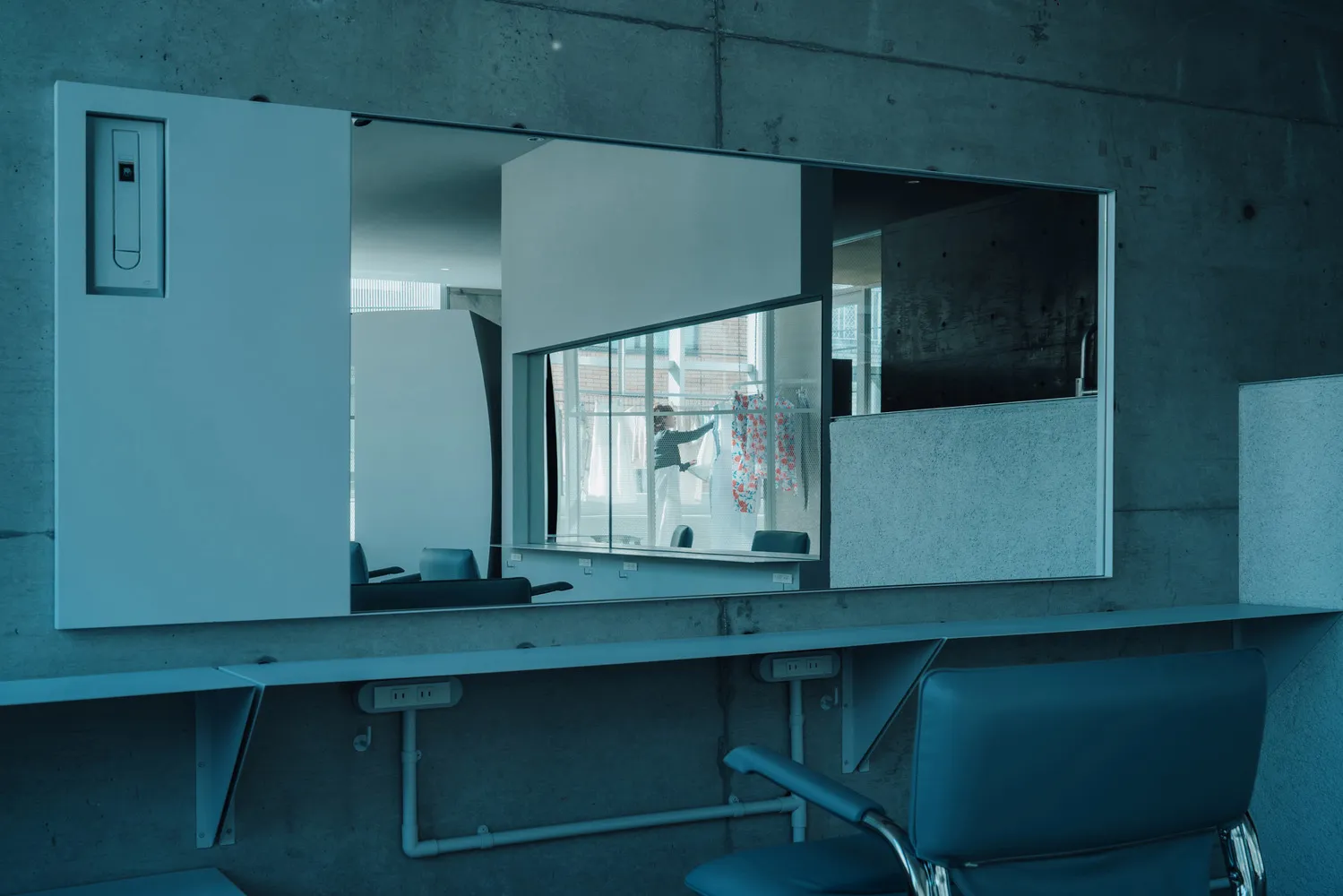An industrial-style minimalist interior featuring a concrete wall and furniture.