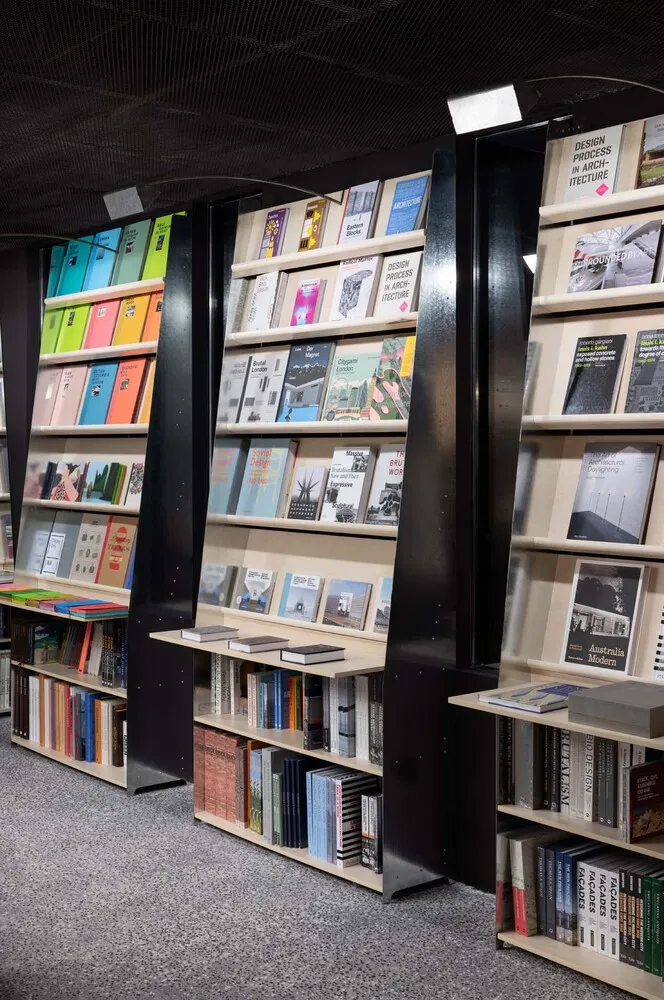 A modern bookstore with tall, sleek shelves displaying colorful books and architectural books.