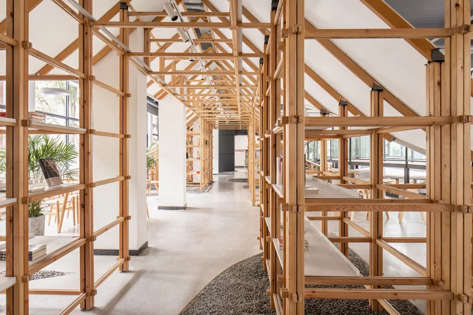 A spacious library interior featuring wooden shelves and a ceiling with exposed beams.
