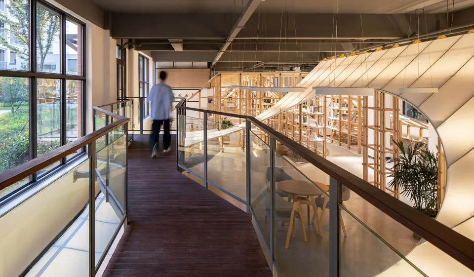 A modern library interior with wooden shelves and tables.