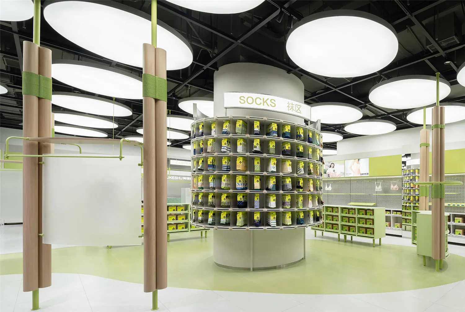 A well-lit, modern retail shop displaying various products on a round shelving unit with a sign labeled 'Socks'.