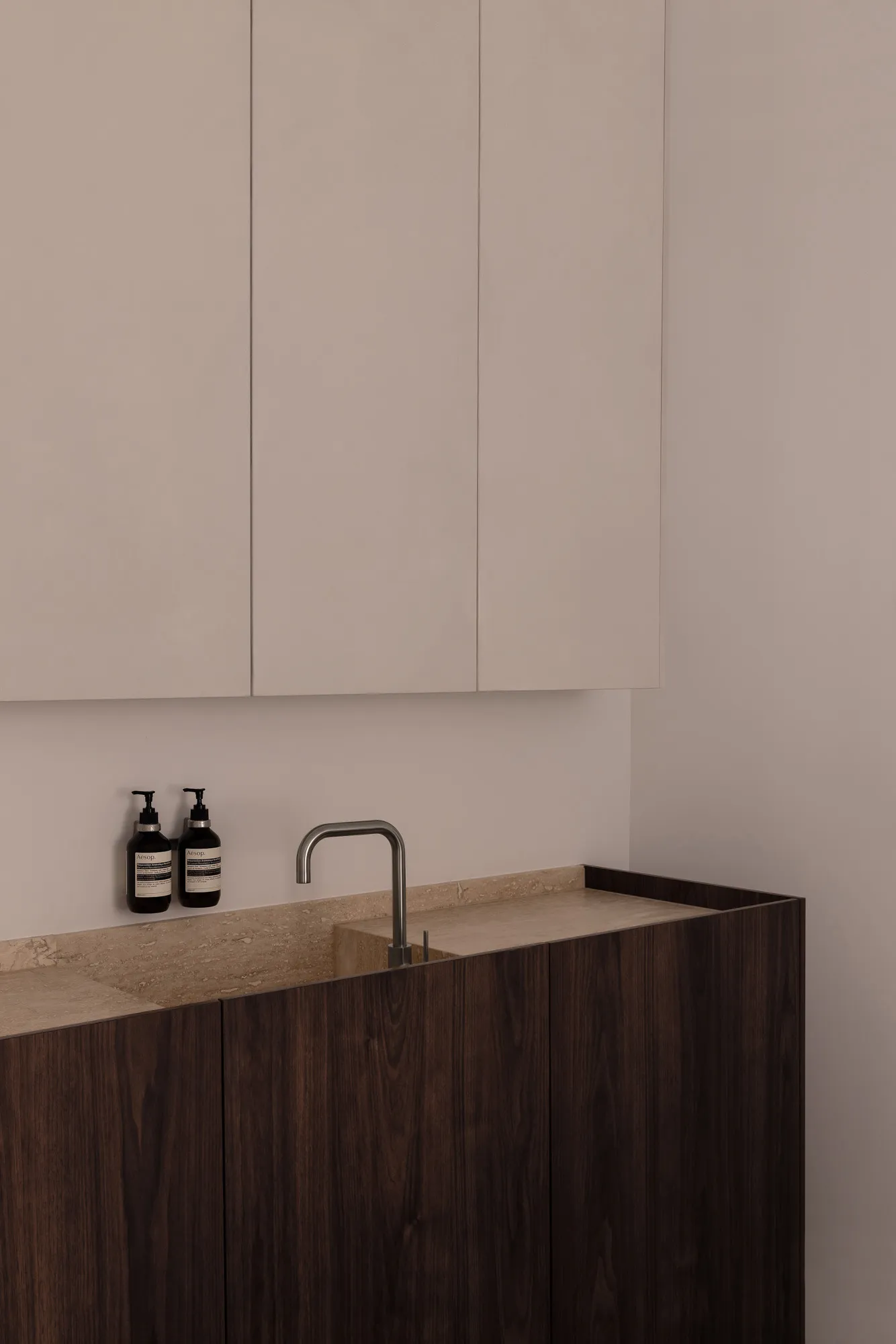 Modern bathroom featuring wooden cabinets, white walls, and a stone countertop with a sink and faucet.