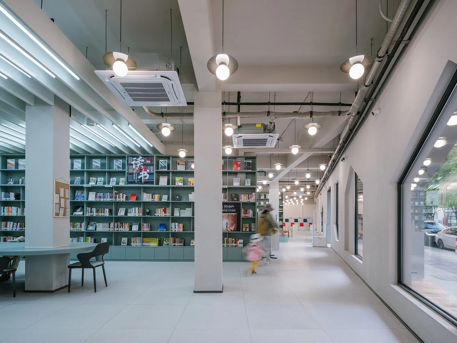 寬敞的現代圖書館室內,混凝土牆面、燈罩與書架。