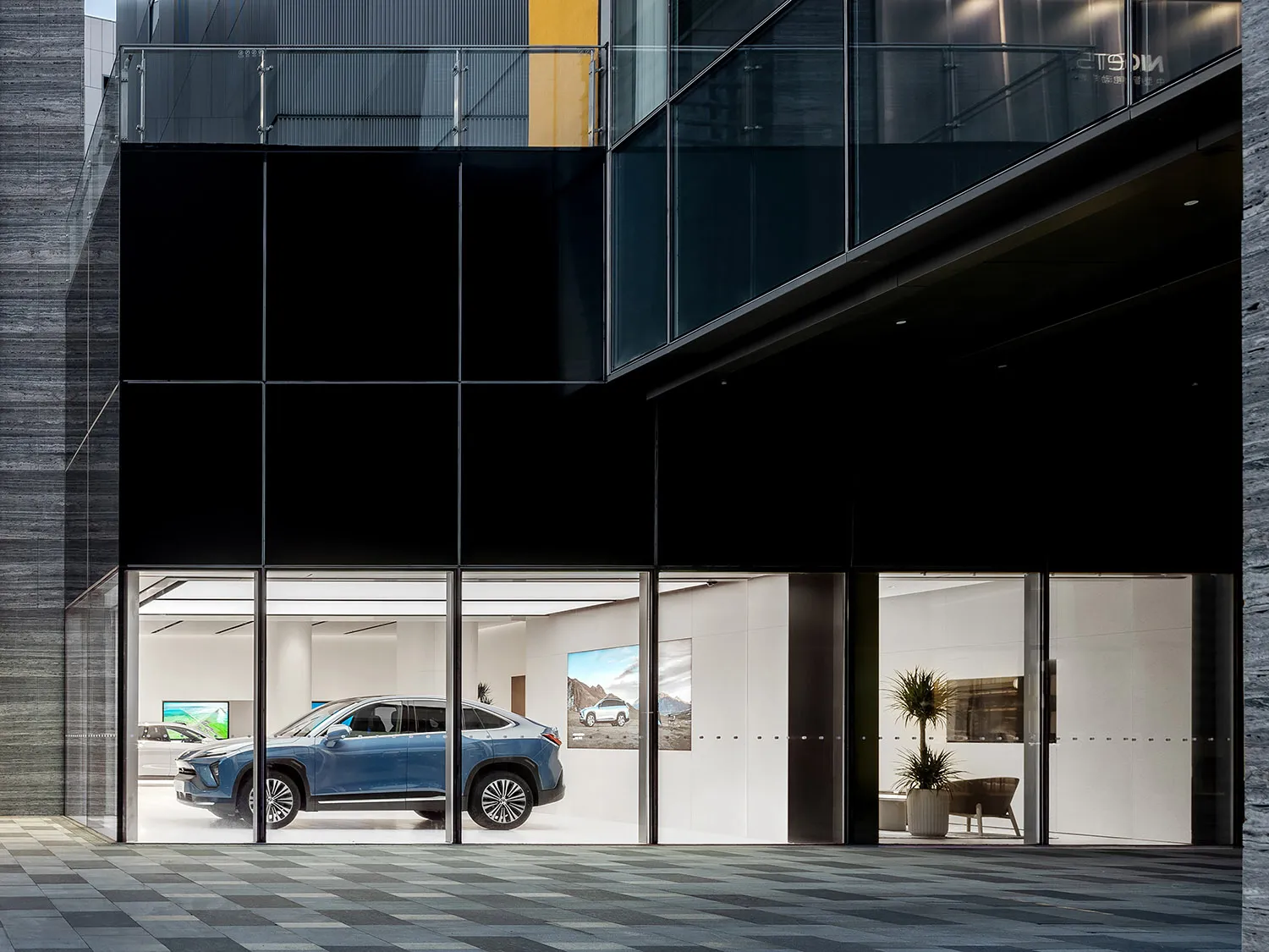 Modern car showroom with glass exterior and concrete interior featuring a blue SUV on display.