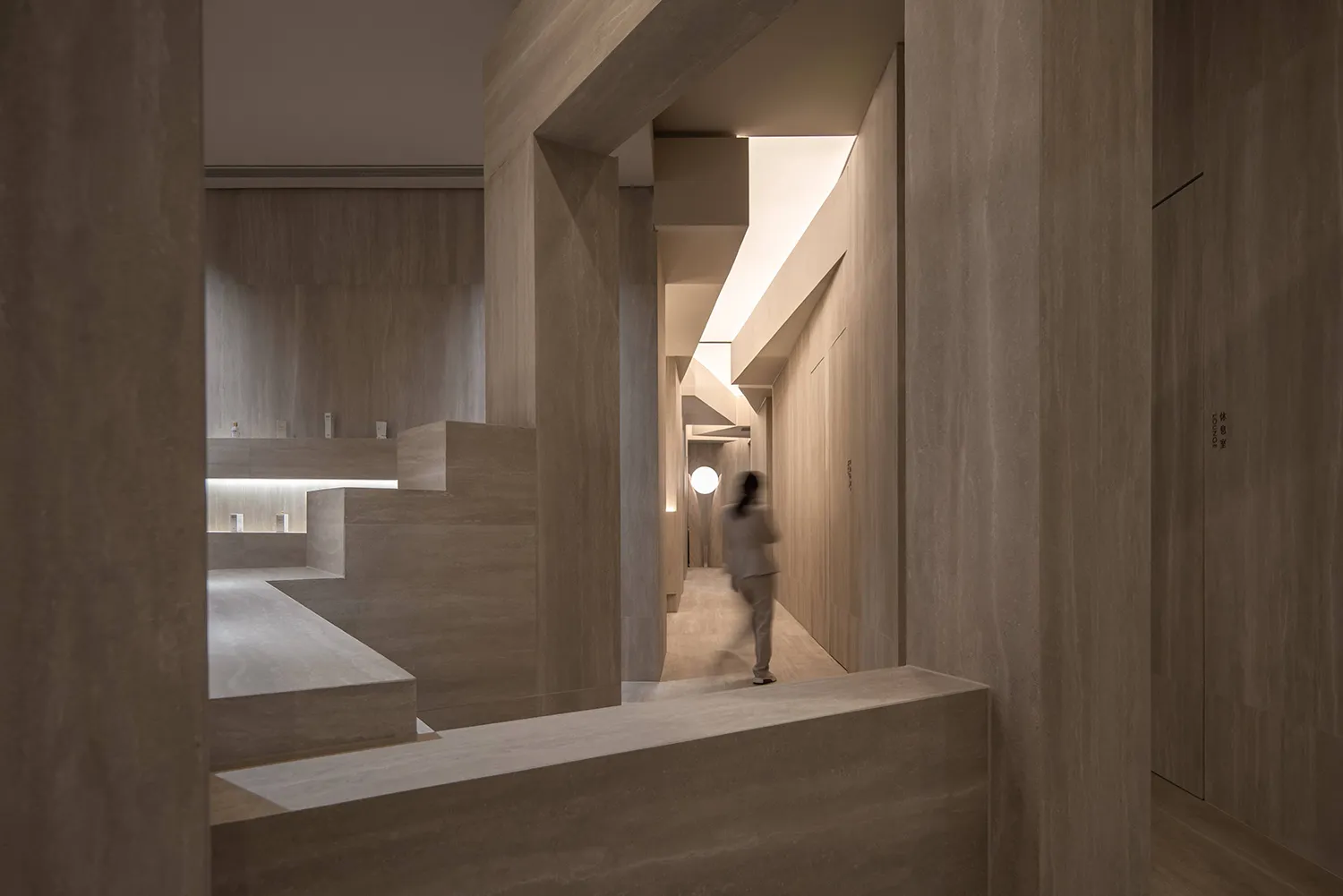 Modern hotel lobby with stone walls and floor, featuring minimalist design elements.