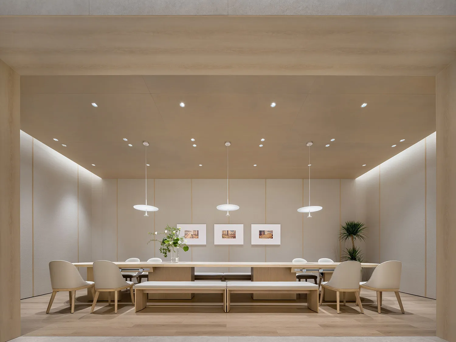 Modern meeting room with wooden tables, chairs, and benches, featuring minimalist design and natural lighting.