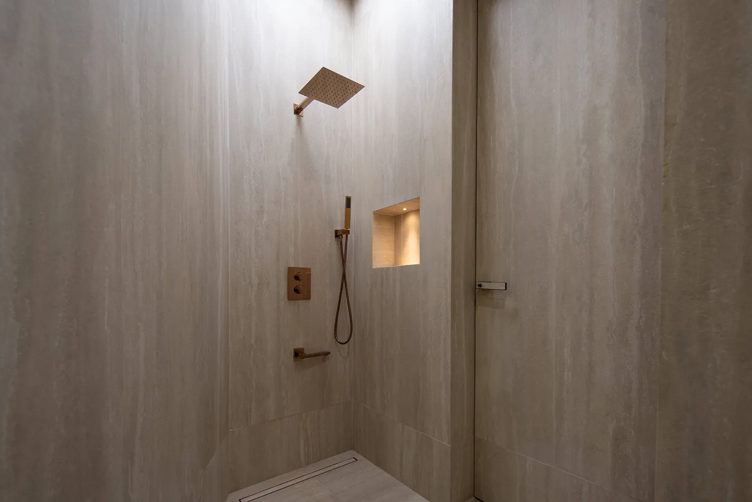 A modern bathroom with a tiled shower area, including a wall-mounted shower head and a handheld shower attachment.