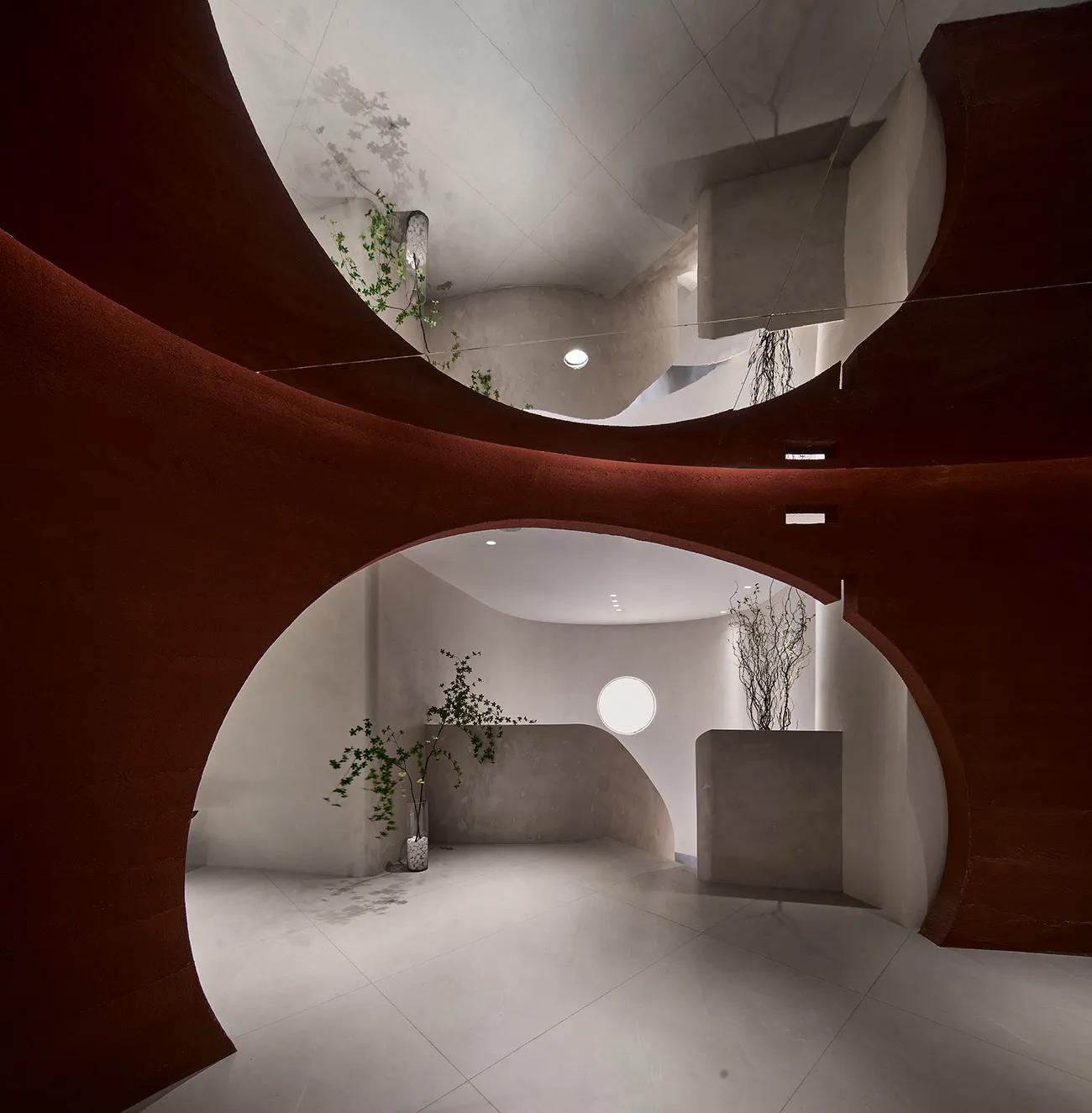 A modern interior space with red curved walls and concrete materials.