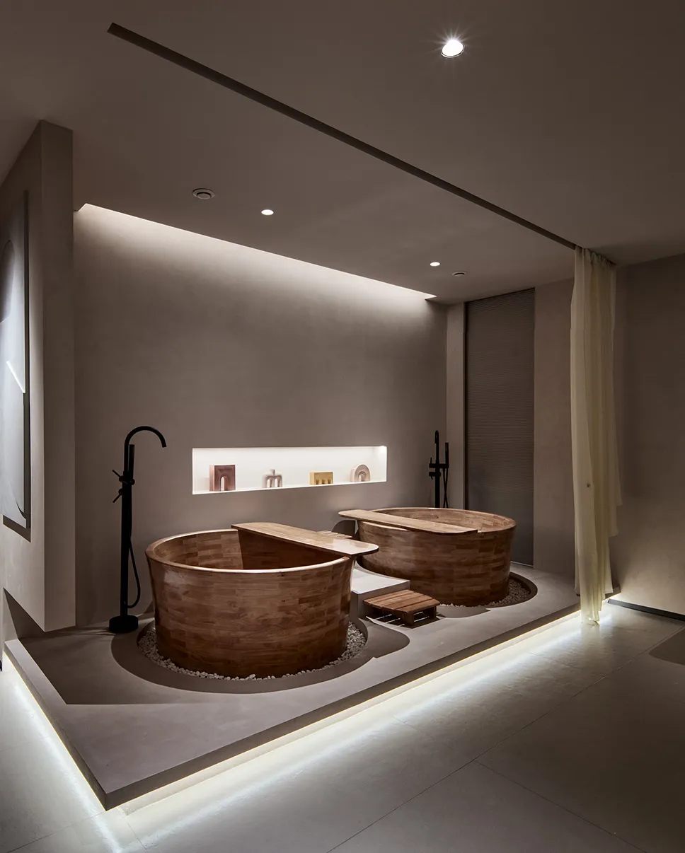 A modern minimalist bathroom featuring concrete and wooden bathtubs.
