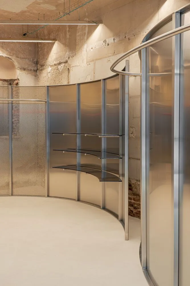 A modern, glass shelving unit with steel elements in retail space