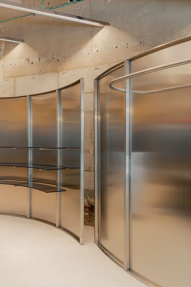 A modern interior space featuring glass walls and shelves.