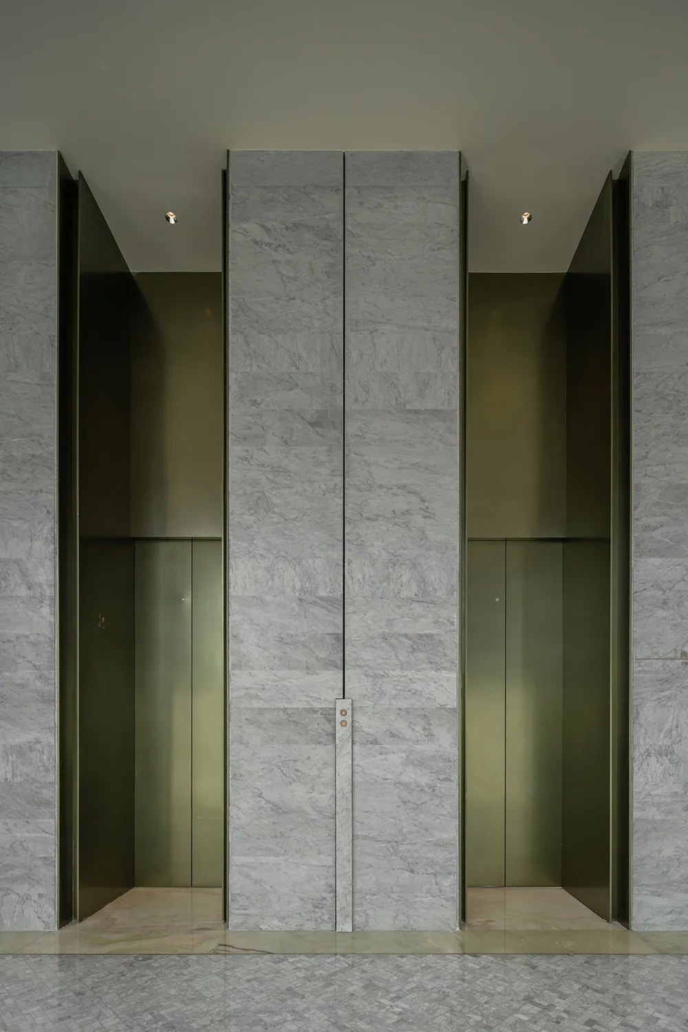 A modern lobby featuring glass elevator doors.