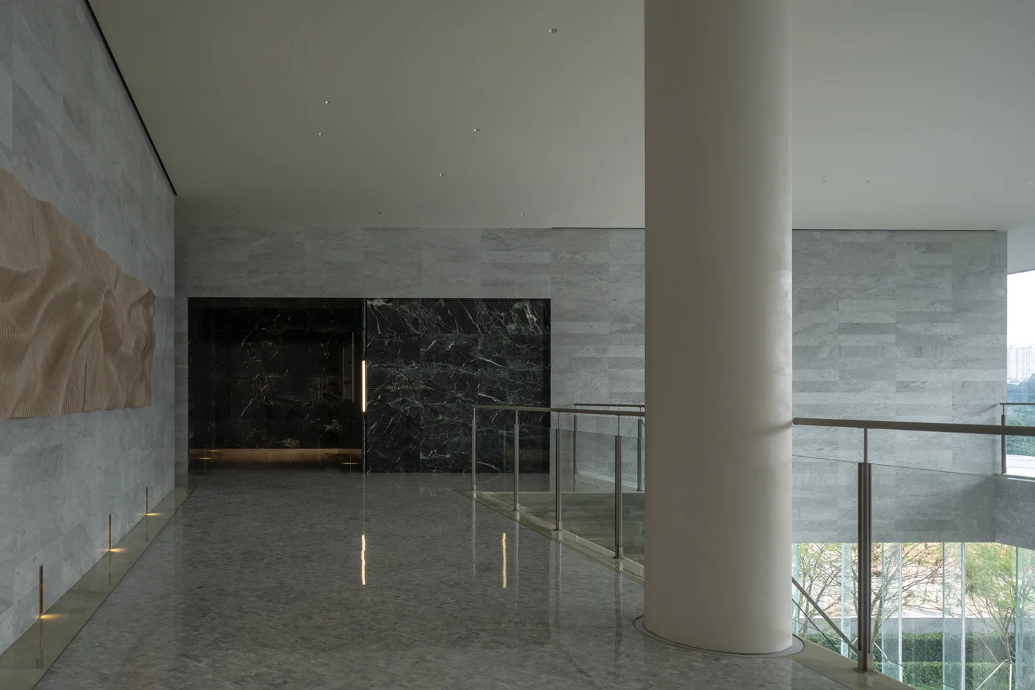 Modern office lobby with marble walls and concrete flooring.