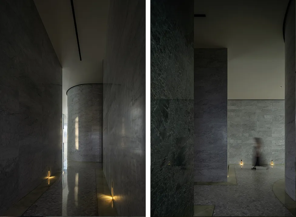 Interior space with dark marble walls and floors, featuring subtle lighting.