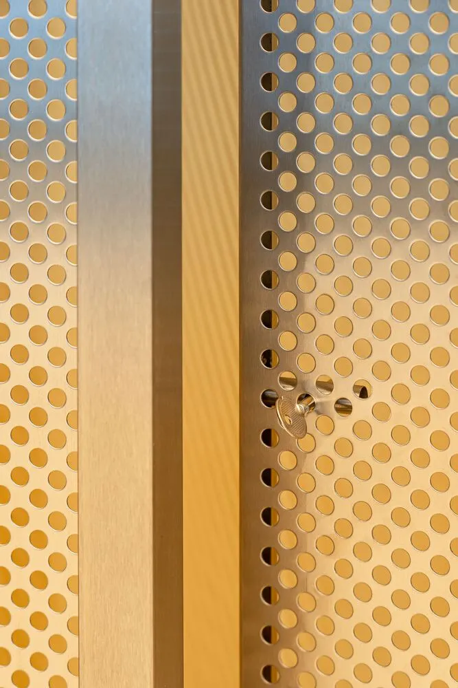 A metallic door with perforated pattern and a key lock mechanism, showcasing industrial design elements.