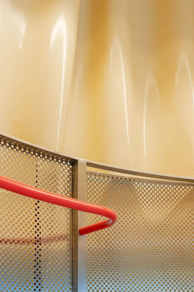 A modern industrial staircase with a red handrail, made of metal.
