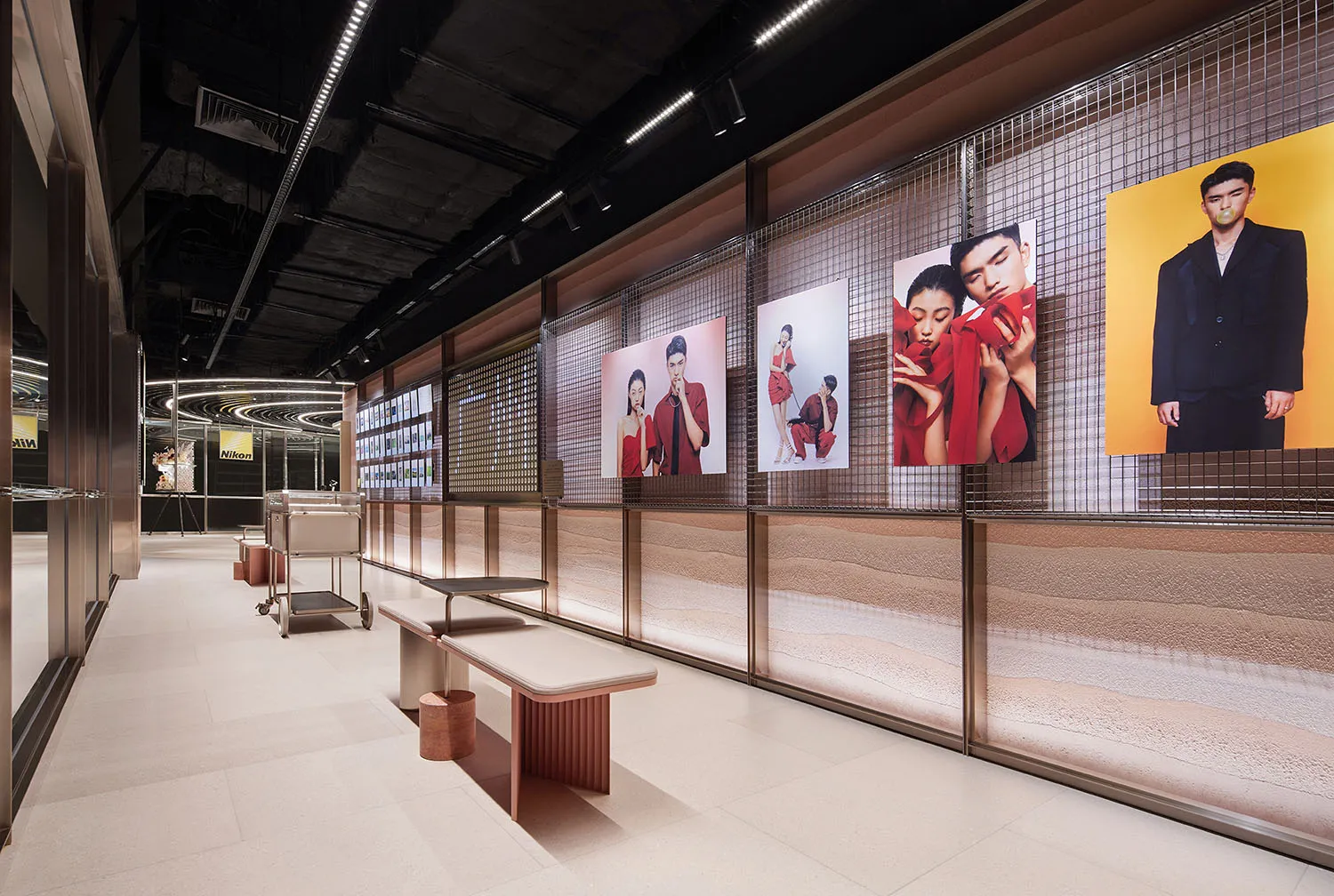 Modern interior design exhibition featuring grid display wall with photographs and metal benches.