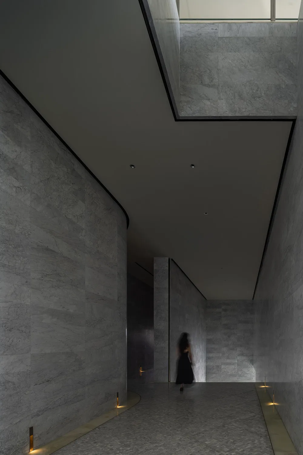 A modern interior space with marble walls and floors, featuring a minimalist design.