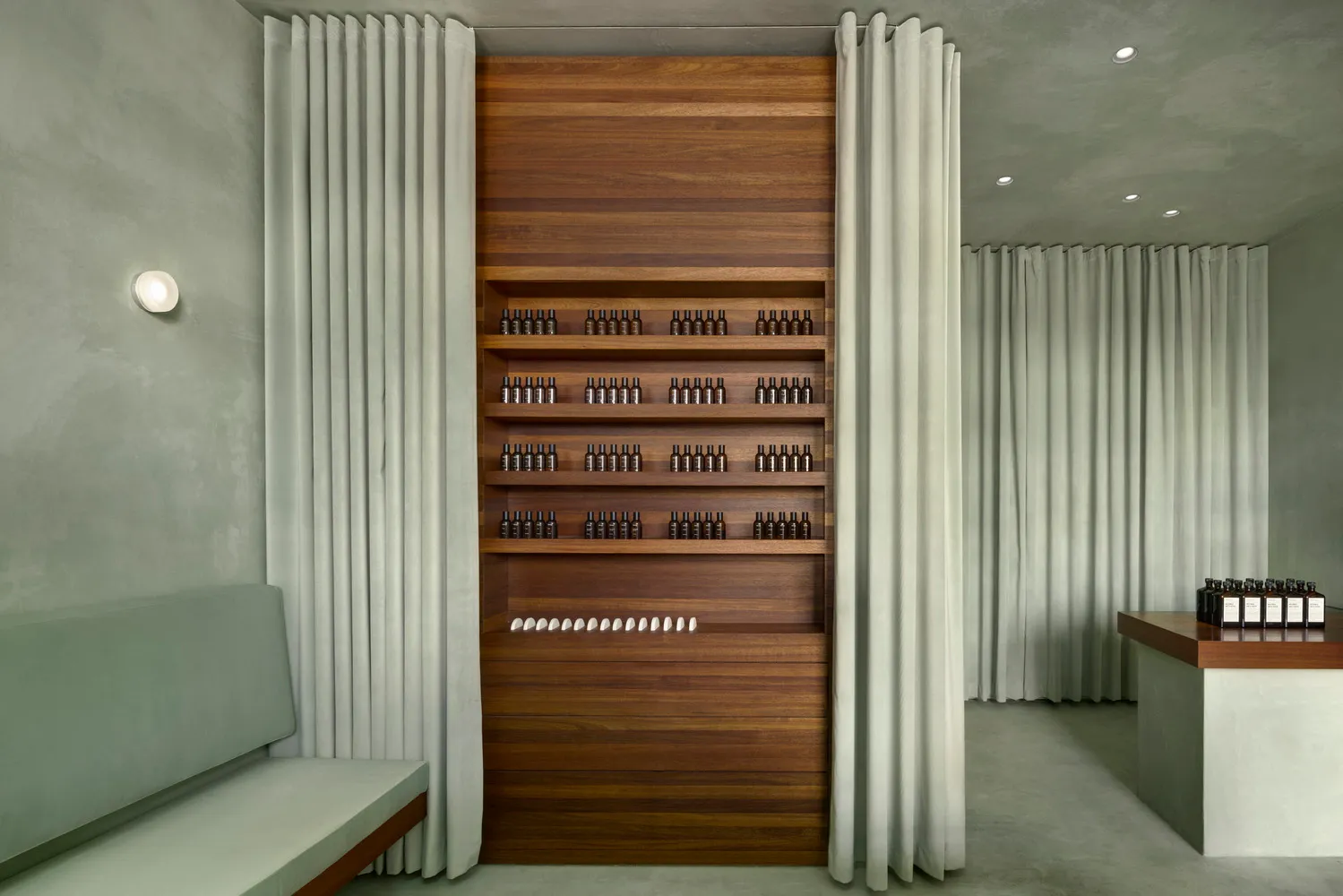 Modern minimalist storefront with concrete walls, wood cabinetry, concrete floors, and a white curtain.