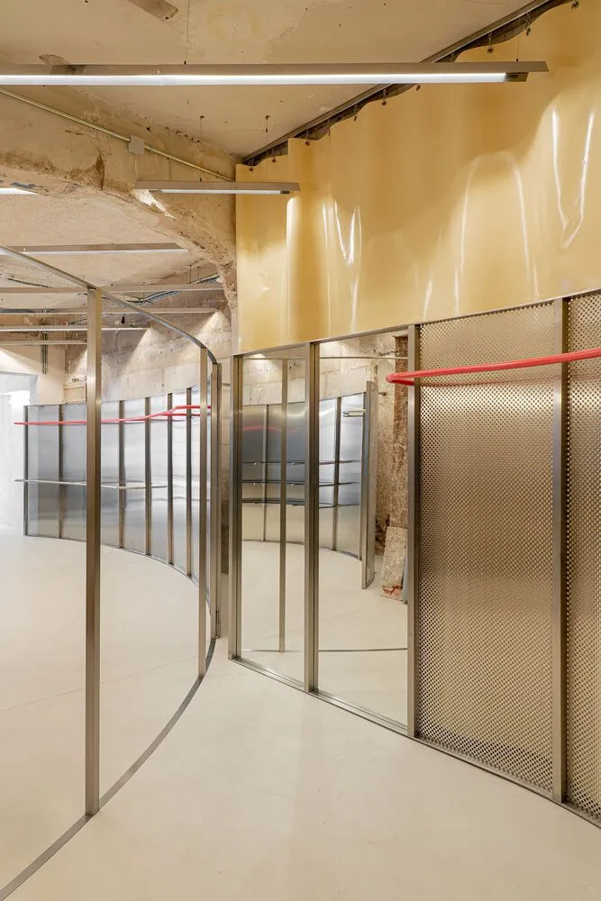 Interior of a modern retail exhibition space with concrete, metallic, and glass materials.