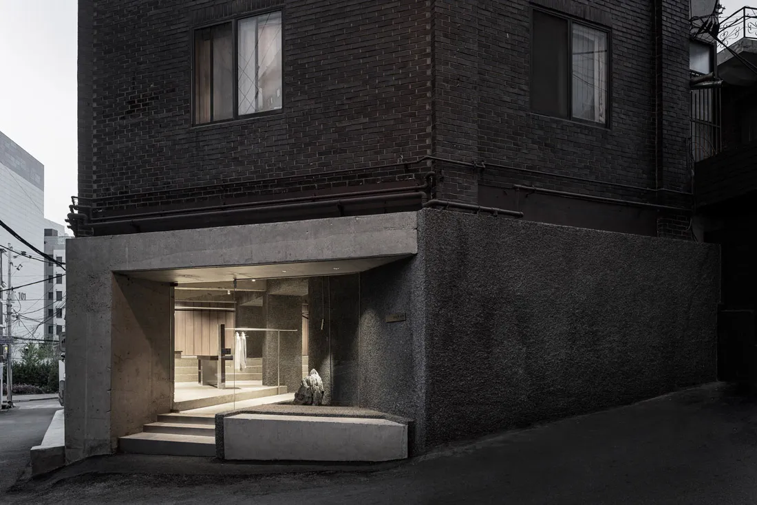 Minimalist storefront with concrete walls and steps leading up to it in an urban setting.