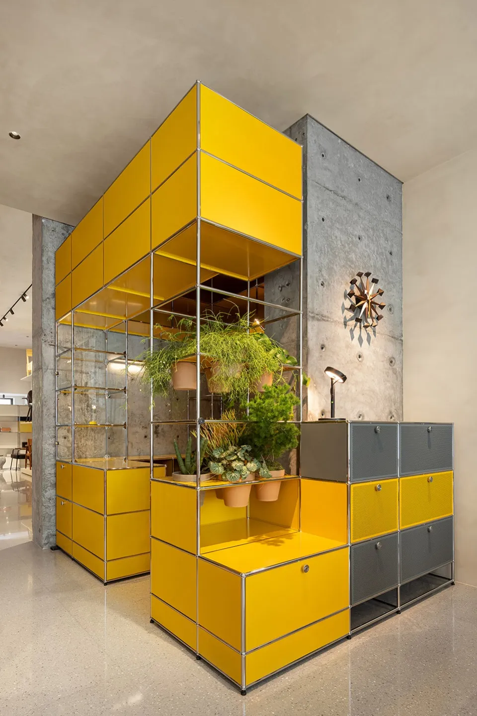 A yellow metallic storage system with shelves and potted plants on metal racks in a retail store environment.
