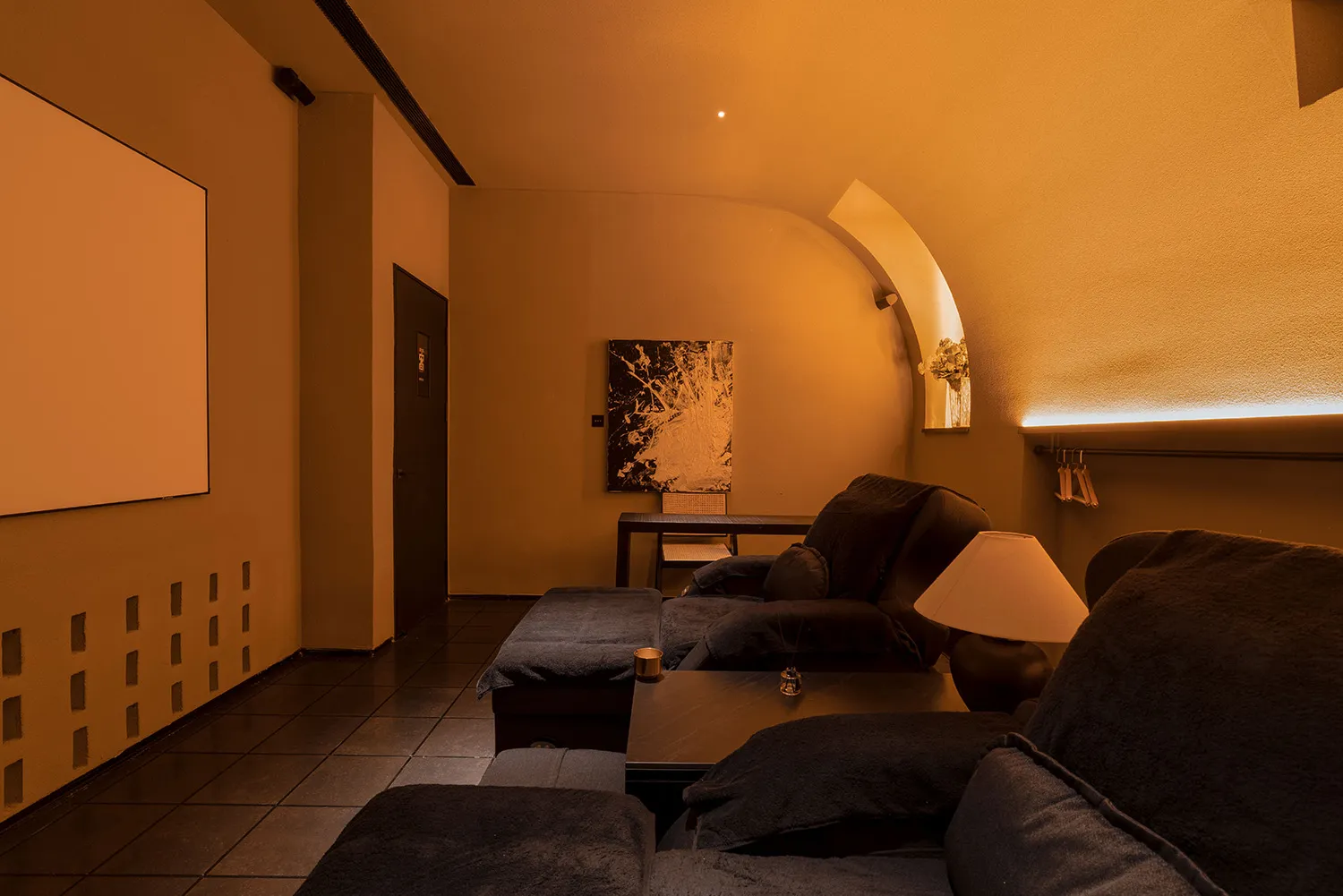 A cozy home theater with minimalist design, concrete flooring, and black furniture.