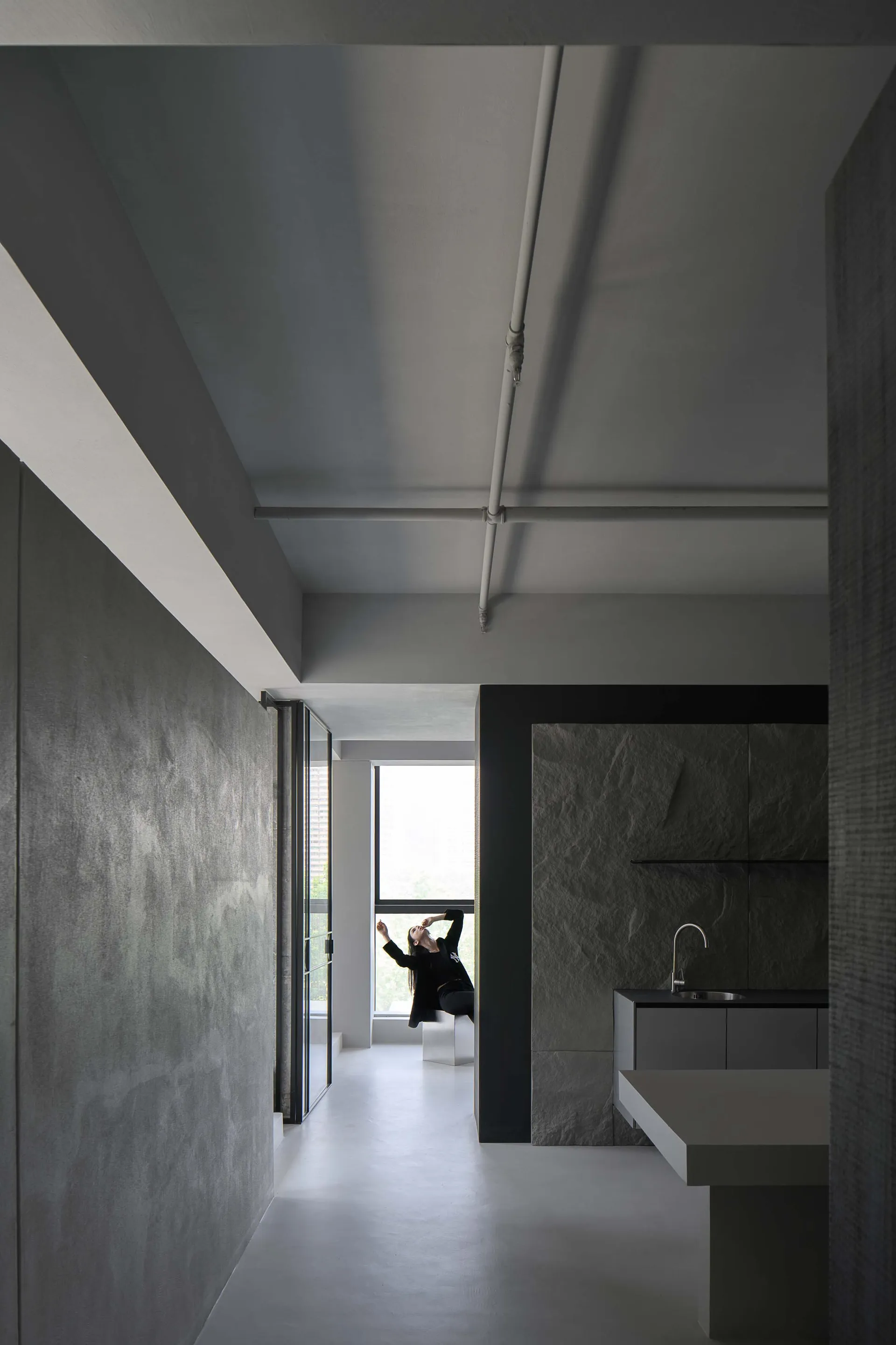 A minimalist modern living space featuring sleek, dark concrete walls and a minimalist design.