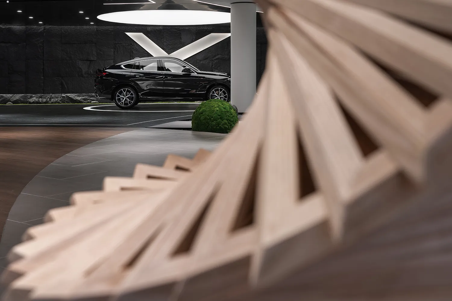 Modern car showroom interior featuring wood elements and a black SUV.