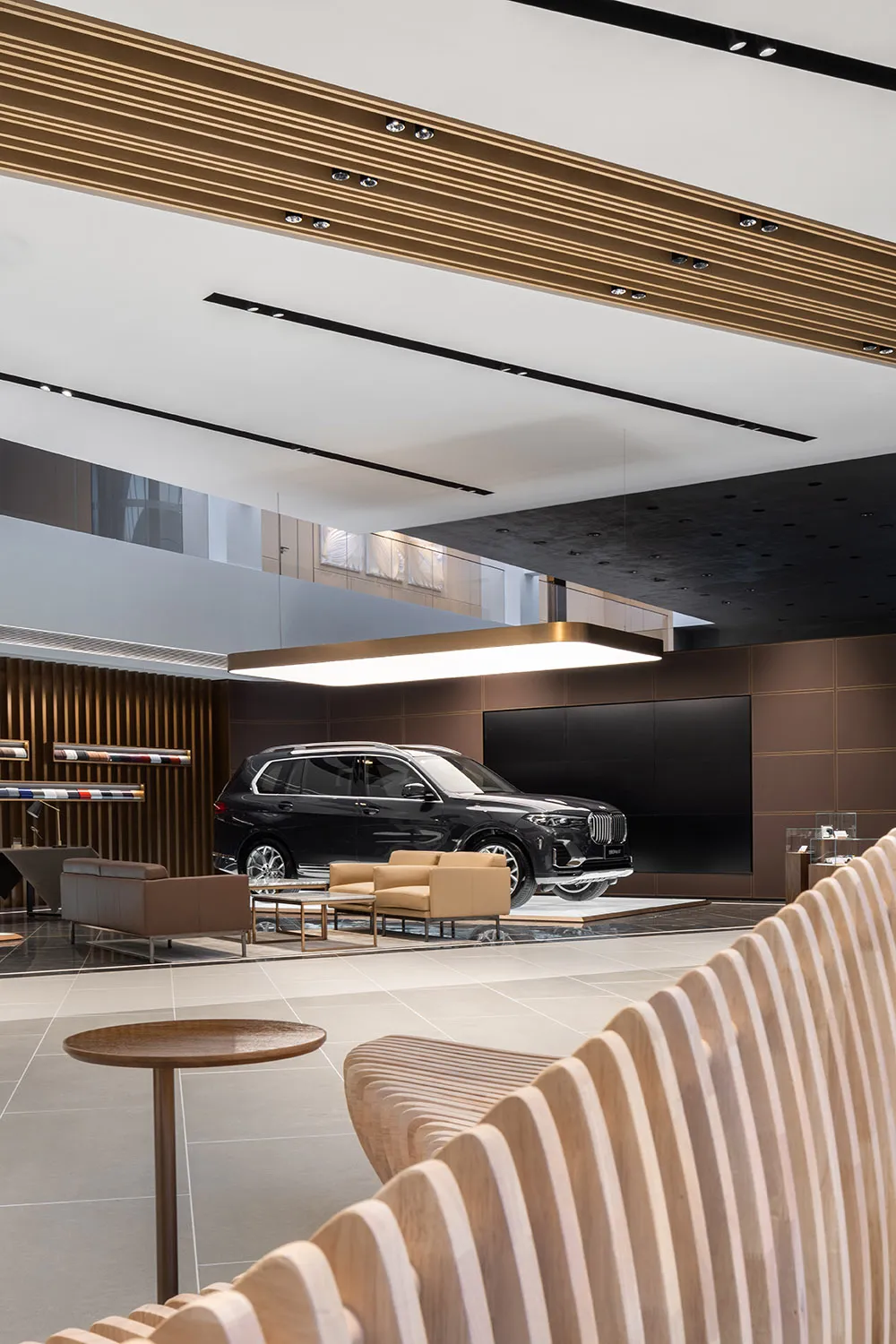 Modern car showroom with a black car on display, surrounded by metal, wood, and glass elements.