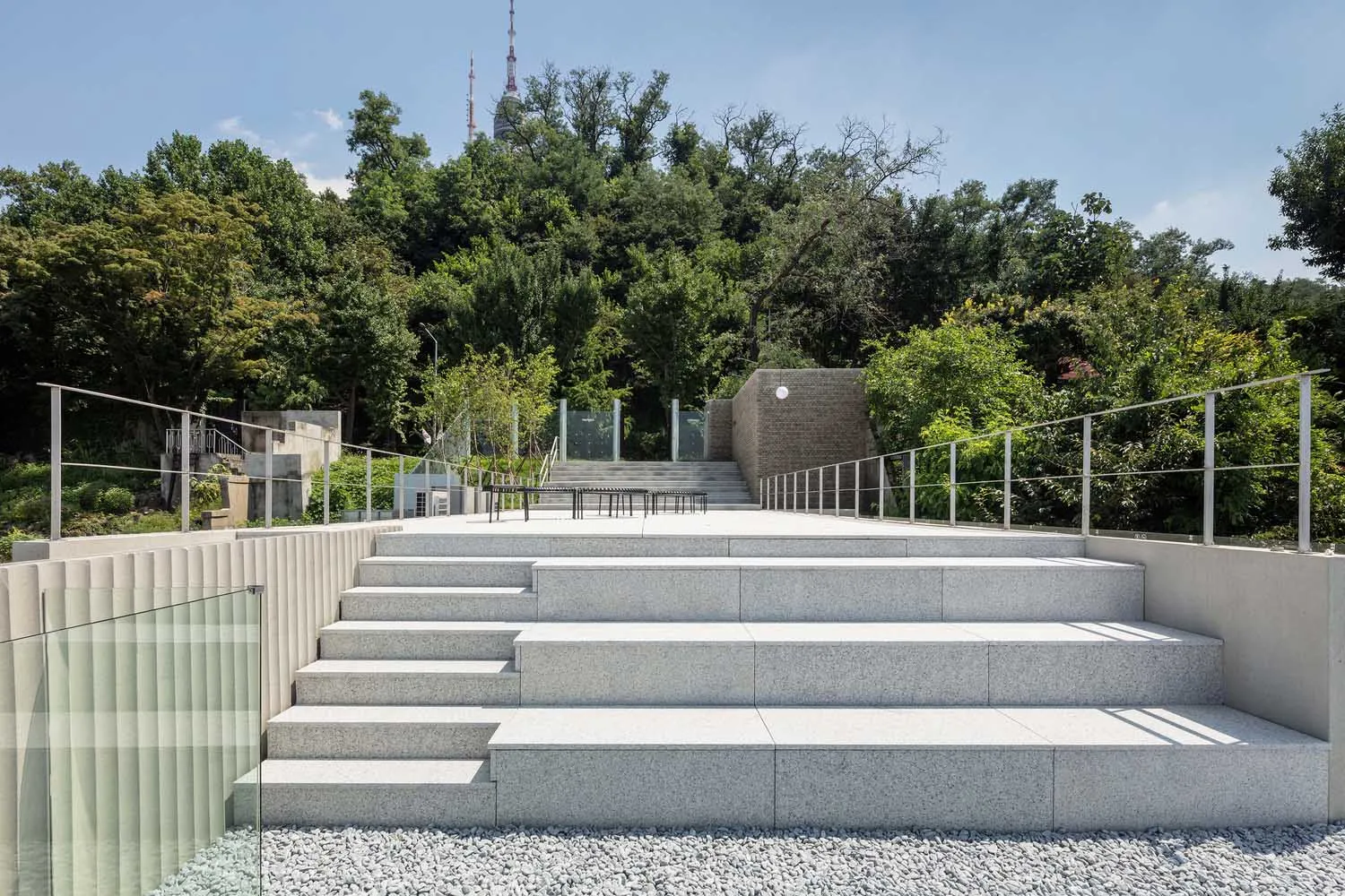 A modern park featuring concrete stairs surrounded by greenery and trees.