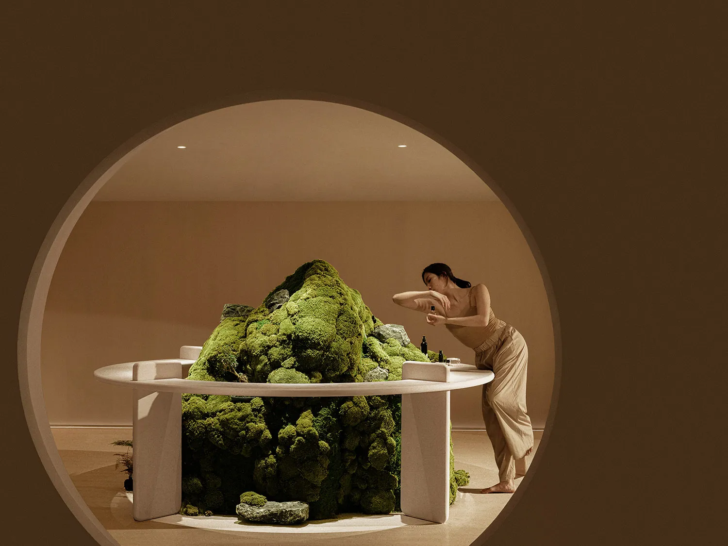 A spa interior with a moss-covered table and a woman leaning over it.