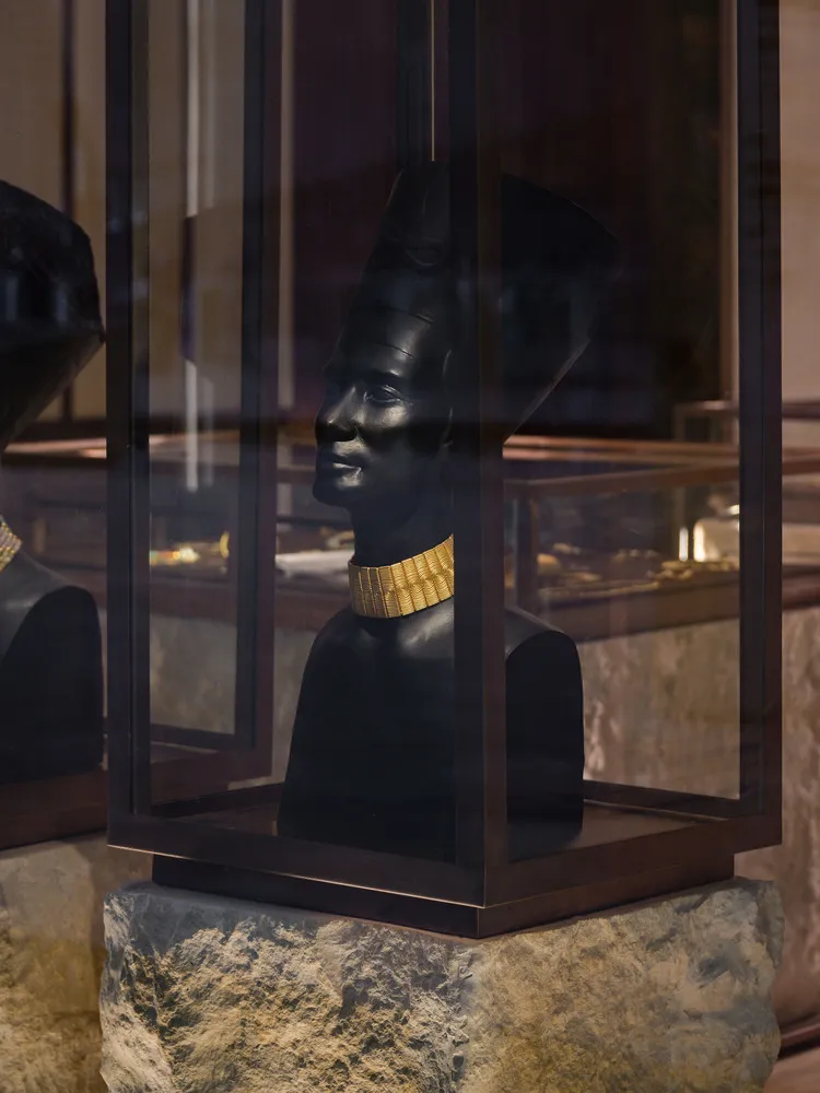 Architectural design of a museum display case featuring a black statue with a gold collar.