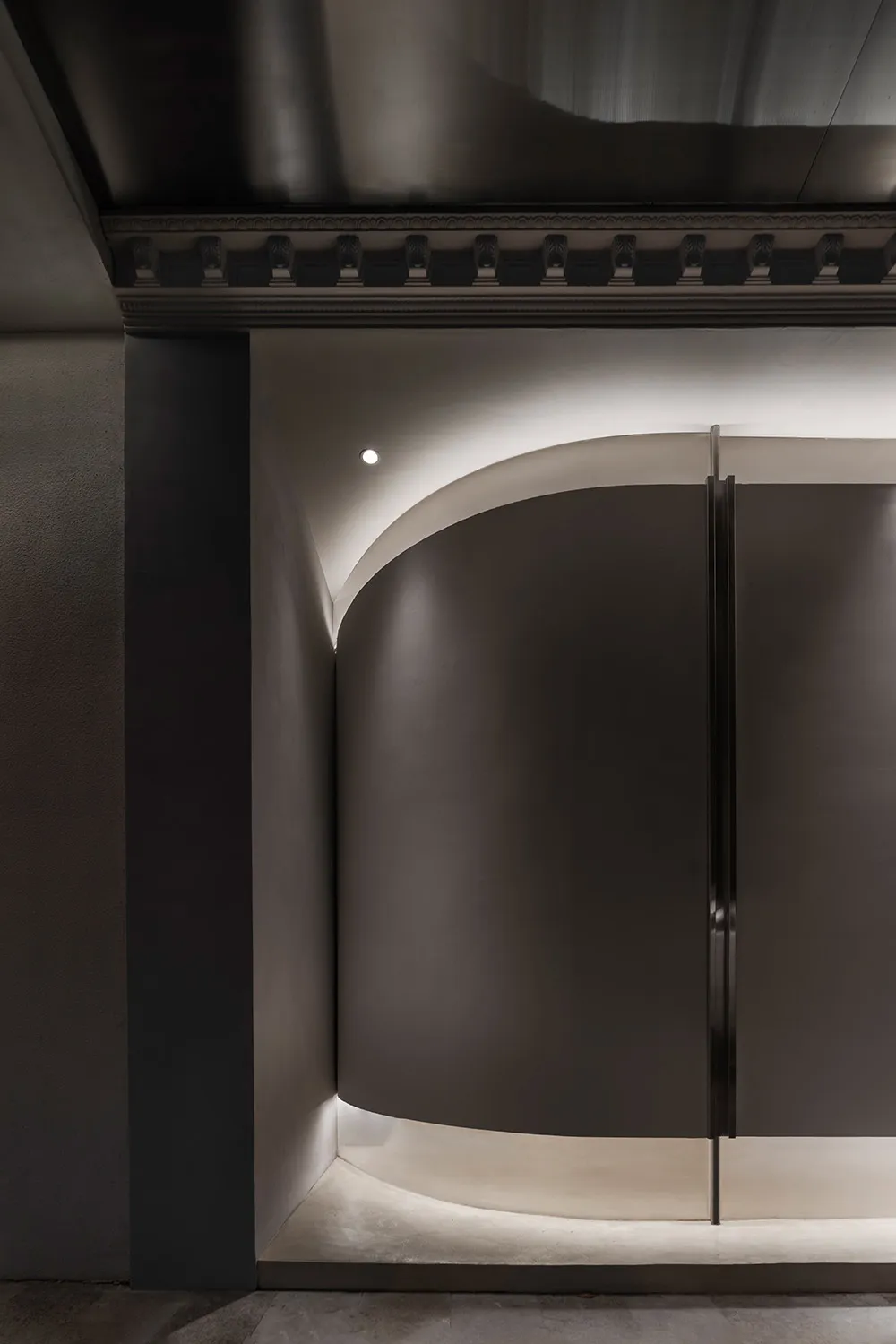 A minimalist interior design space featuring metal elements and curved walls.