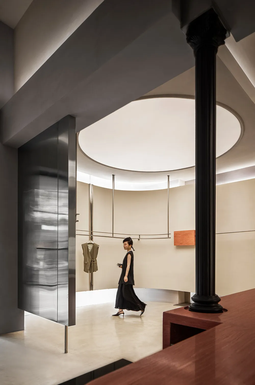 A minimalist clothing store features concrete, metal, and wood materials.