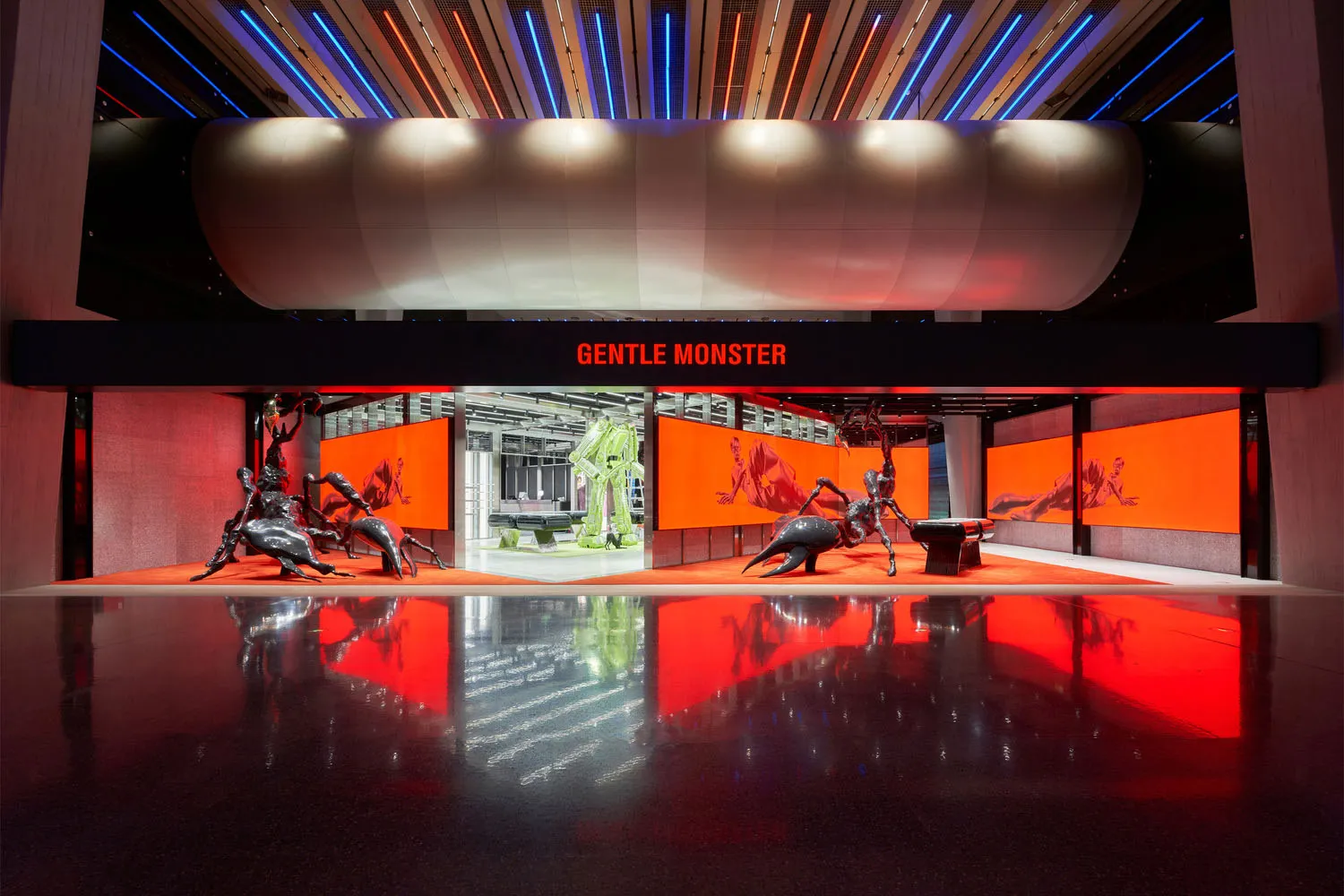 A retail interior with metal sculptures on a reflective floor, illuminated by bright lights.