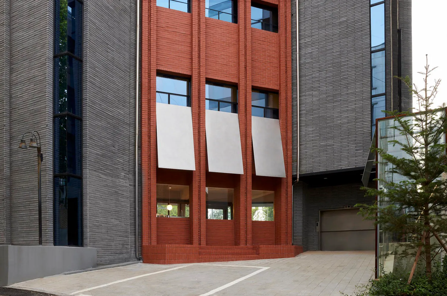 Modern building exterior featuring brick walls, concrete elements, and aluminum accents.